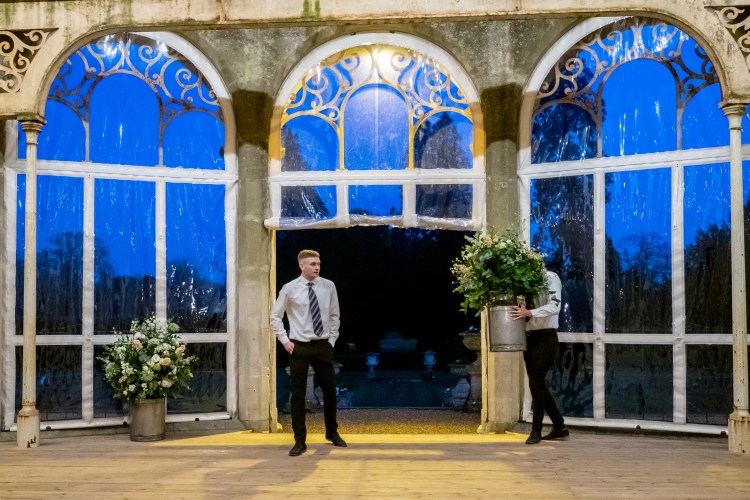 A wedding vendor carrying a plant pot at Grittleton House in Wiltshire.