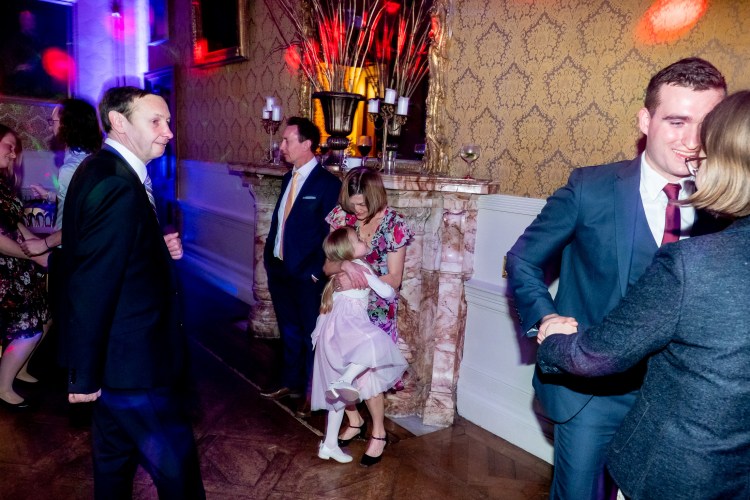 A young guest cuddles her mother during an evening wedding reception at Grittleton House in Wiltshire.