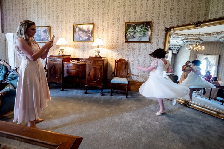 A flower girl dances in front of a mirror ahead of a wedding at Grittleton House in Wiltshire.