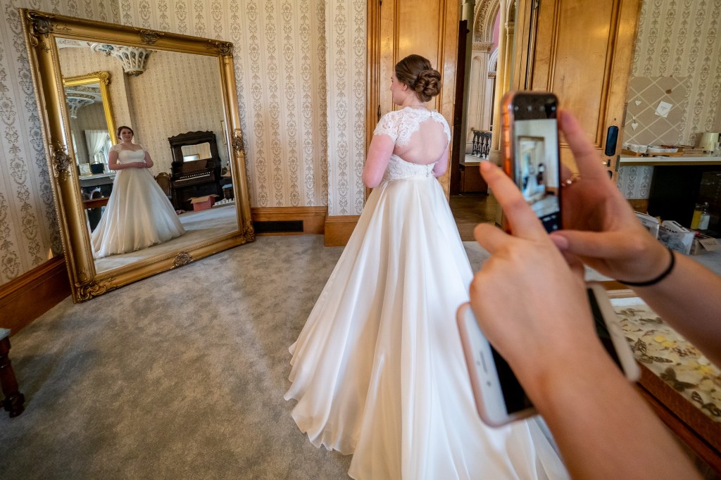 The bride poses in a mirror during morning preparations at Grittleton House in Wiltshire.