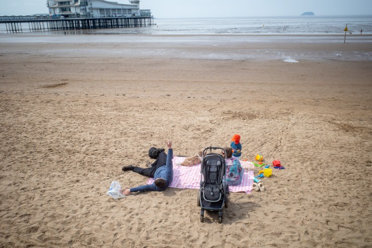 Candid street photography of a man falling backwards on the beach in Weston-super-Mare