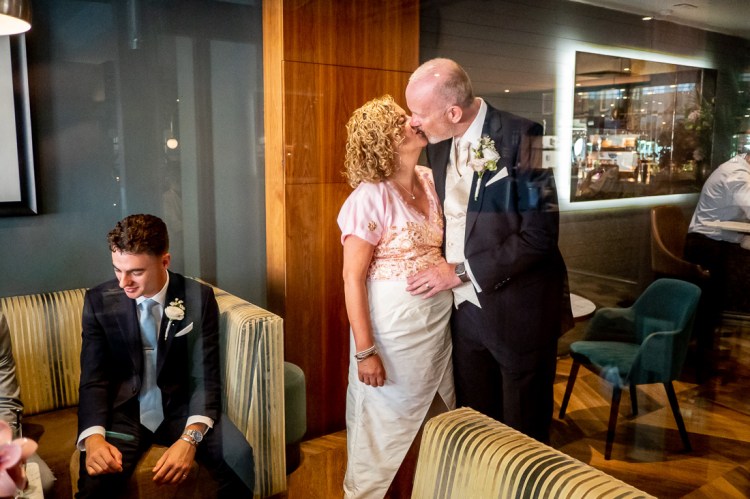 The bride and groom kiss in a bar during their wedding in Bristol. 
