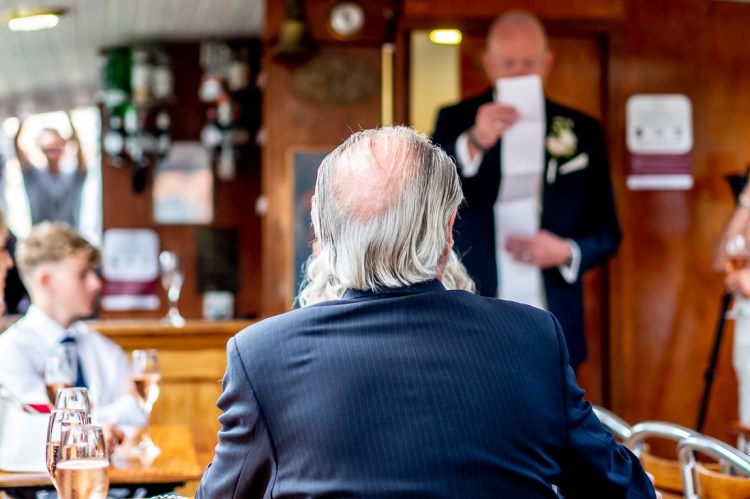 A guest looks on as the groom reads his speech, during a Bristol wedding on the Flower of Bristol boat, run by Bristol Packet tour company.