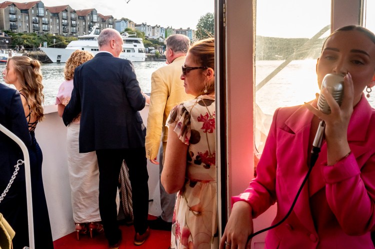 THe wedding party look out across the River Avon, whilst the singer performs, during a Bristol wedding on the Flower of Bristol boat, run by Bristol Packet tour company.