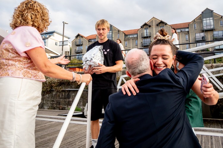 The groom hugs the food company as they deliver food, during a Bristol wedding on the Flower of Bristol boat, run by Bristol Packet tour company.