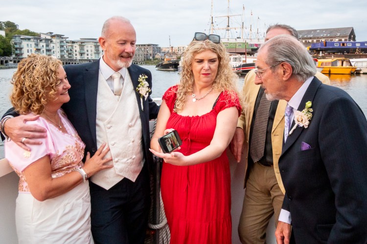 The bride, grrom and guests enjoy a phone photo, during a Bristol wedding on the Flower of Bristol boat, run by Bristol Packet tour company.
