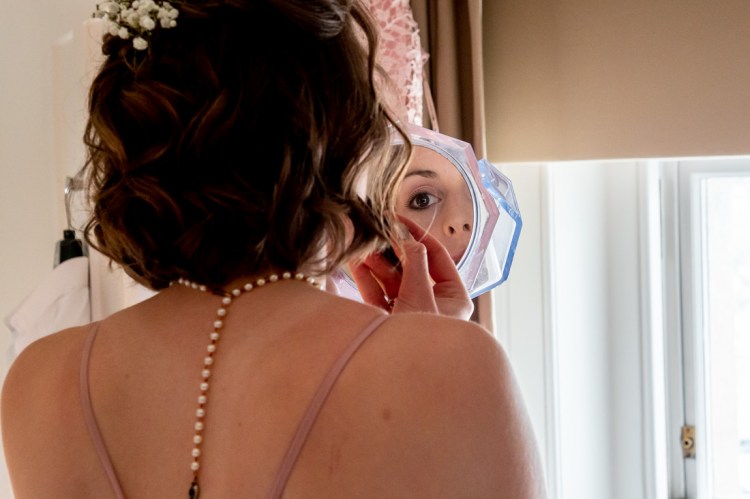 A bridesmaid applies makeup, during the morning preparations, ahead of a wedding at Worcester College in Oxford.