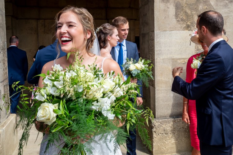 A laughing bride with flowers during a wedding at Worcester College in Oxford.