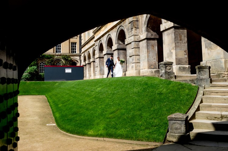 THe bride and groom walk through the grounds, during a wedding at Worcester College in Oxford.