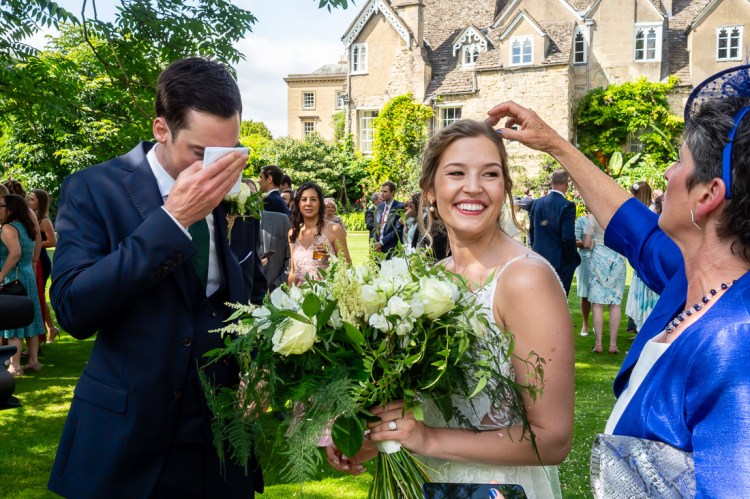 The groom wipes his brow, as a guest picks confetti out of the bride's hair, during a wedding at Worcester College in Oxford.