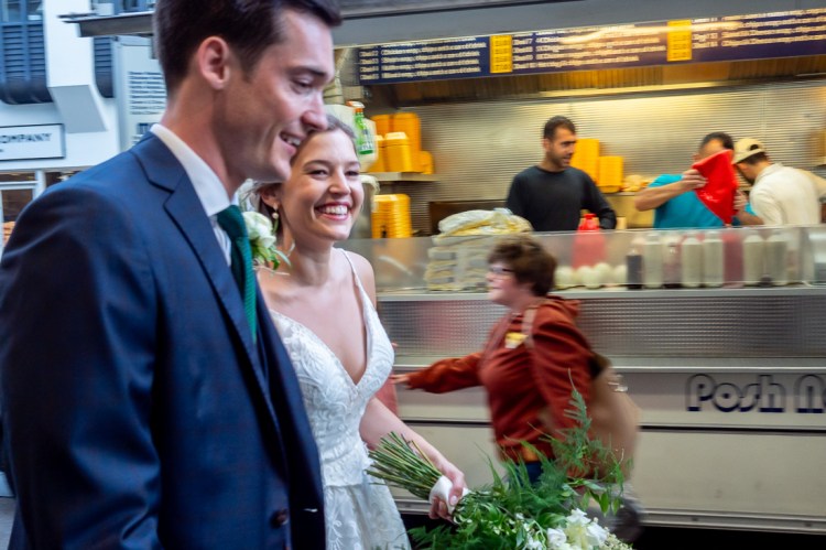 The bride and groom walk past a street food trailer during a wedding day in Oxford.