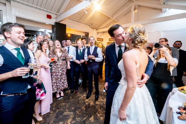 Guests look on as the bride and groom kiss at the Jam Factory during a wedding in Oxford.