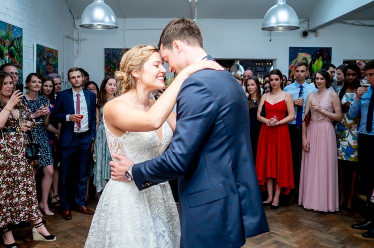 The bride groom enjoy their first dance, watched by guests, during the evening wedding reception at the Jam Factory in Oxford.