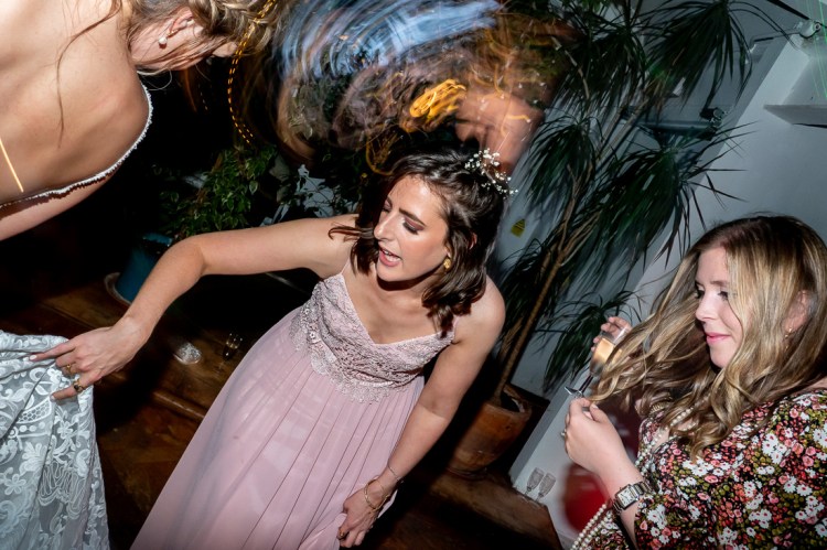 A bridesmaid sorts out the bride's dress, during the evening wedding reception at the Jam Factory in Oxford.