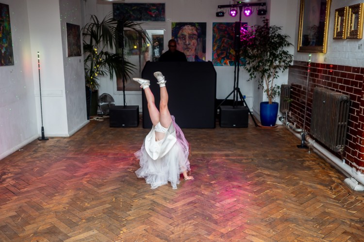 The young flower girl dance a handstand on the dancefloor, during the evening wedding reception at the Jam Factory in Oxford.