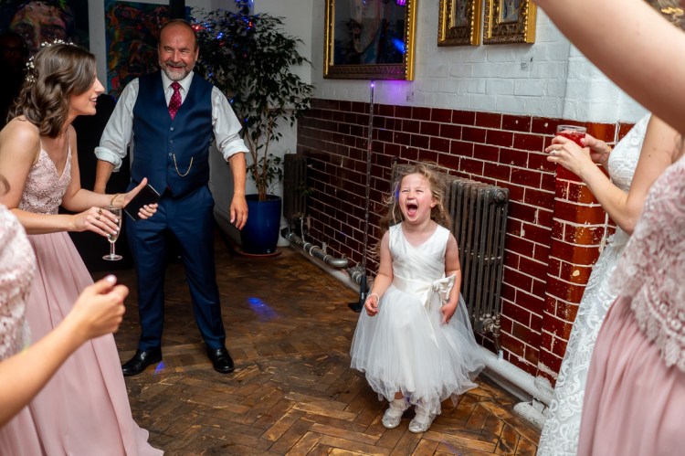 The flower girl screams excitedly on the dancefloor, during the evening wedding reception at the Jam Factory in Oxford.