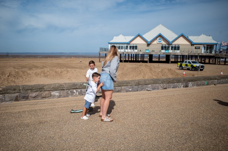 Candid street photography of a boy sniffing his mum's bum on the seafront in Weston-super-Mare, North Somerset, UK.