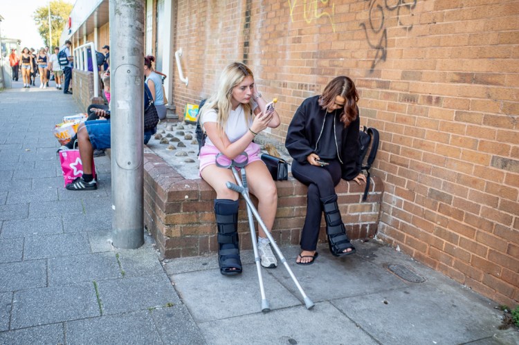 Candid street photography of two girls with broken legs in Weston-super-Mare, North Somerset, UK.