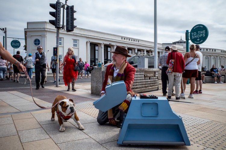 Candid street photography of a bulldog and K9 robot dog and Doctor Who in Weston-super-Mare, North Somerset, UK.