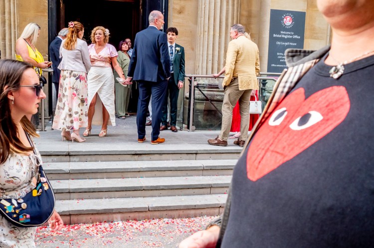 A man with a love heart t shirt passes the wedding party, during a wedding at Bristol Register Office