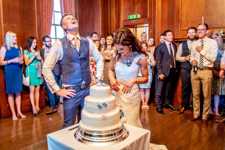 The groom laughs during the cutting of the wedding cake at Gatton Hall in Surrey.