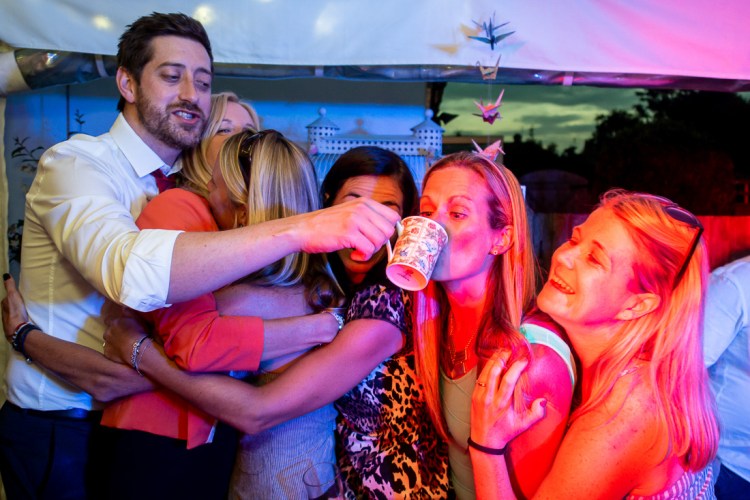 Guests enjoy a cup of tea on the dancefloor during a backyard wedding in New Malden, London.