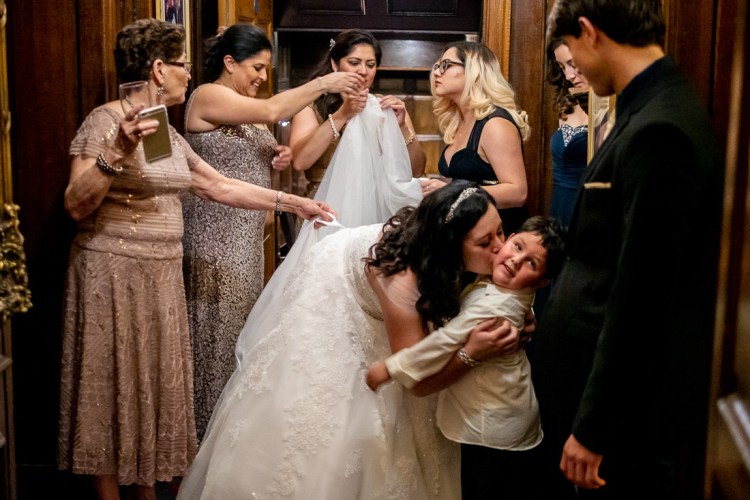 The bride kisses a young guest, as the bridal party fixes her dress, during a wedding at Rowton Castle in Shropshire.