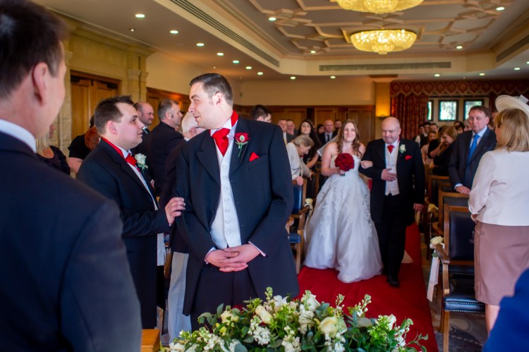 The best man places a reassuring hand on the grooms arm, as the bride comes up the aisle during a wedding at South Lodge Hotel, near Horsham in Sussex.