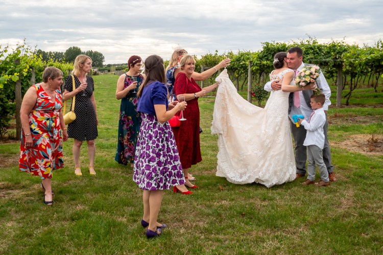 A guest adjusts the brides dress during a wedding at Highdown Vineyard in West Sussex.